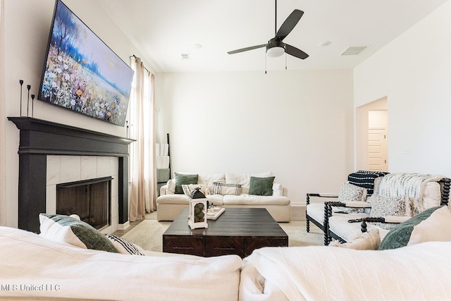 carpeted living area featuring a tile fireplace, visible vents, and ceiling fan