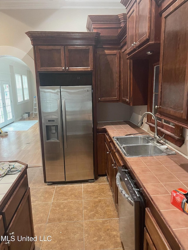 kitchen with appliances with stainless steel finishes, tile countertops, light hardwood / wood-style flooring, dark brown cabinetry, and sink