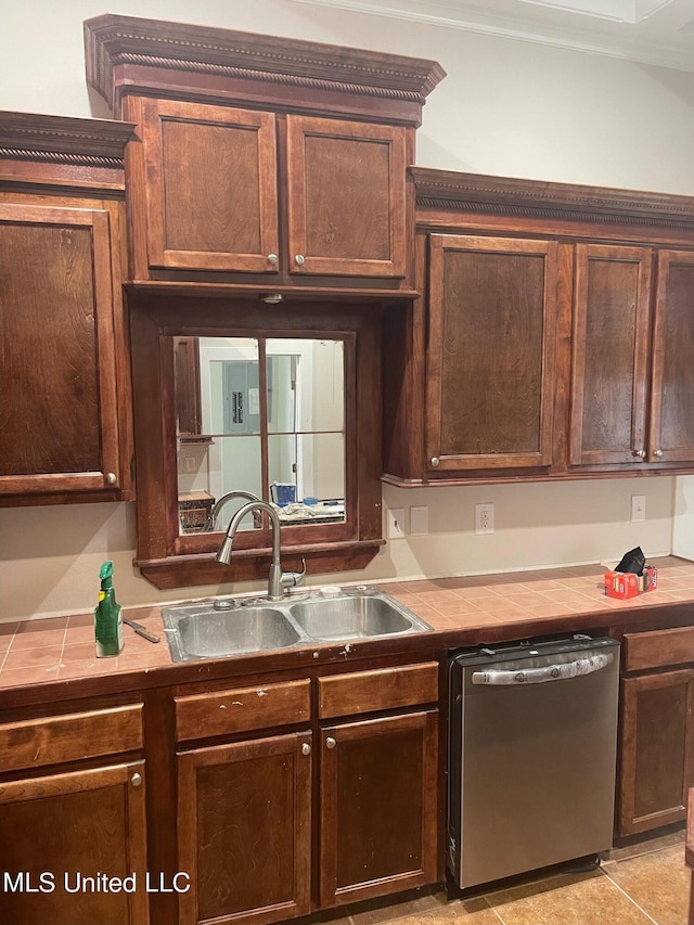 kitchen featuring dark brown cabinetry, stainless steel dishwasher, sink, and light tile patterned floors