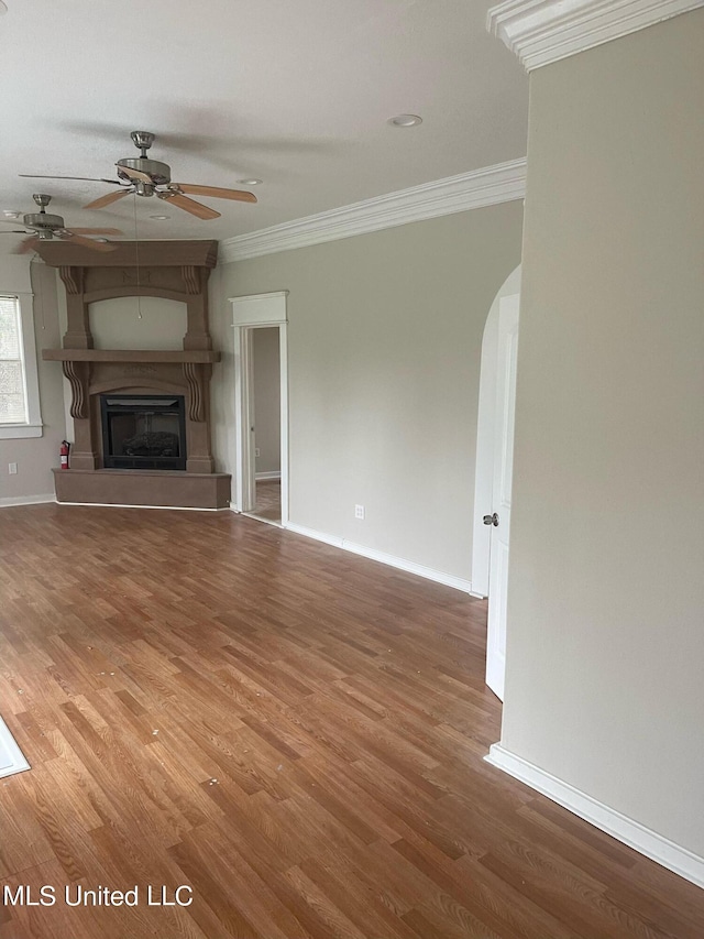 unfurnished living room with ceiling fan, hardwood / wood-style flooring, ornamental molding, and a fireplace