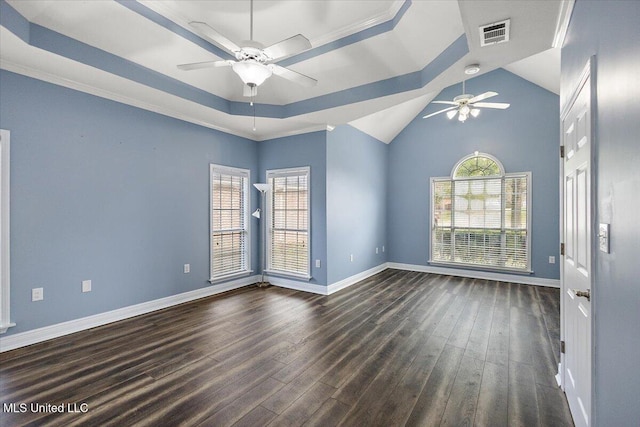 empty room featuring a raised ceiling, plenty of natural light, dark hardwood / wood-style floors, and ornamental molding