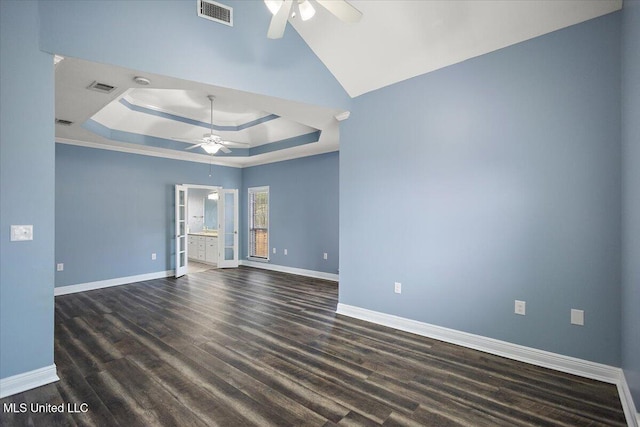 unfurnished room with ceiling fan, a raised ceiling, and dark wood-type flooring