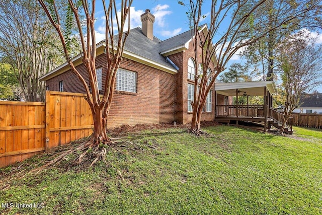 exterior space featuring a deck, ceiling fan, and a lawn