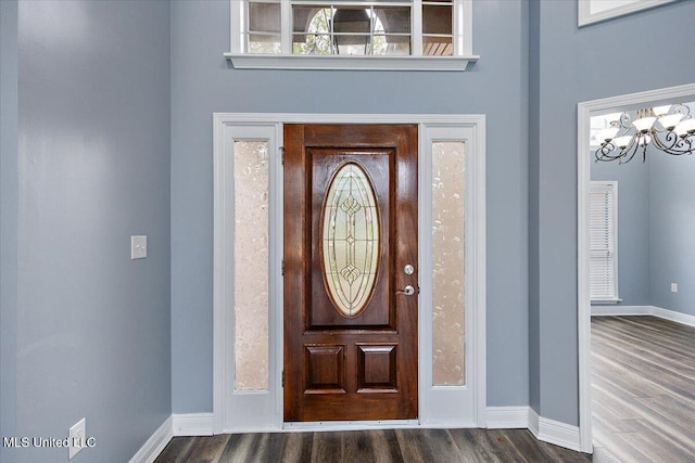 entryway featuring a towering ceiling, dark hardwood / wood-style floors, and a notable chandelier