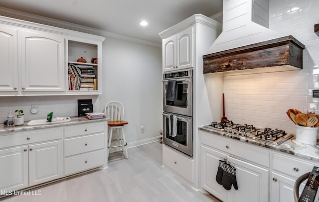 708 Oak Trl, Canton, MS 39046 - kitchen featuring appliances with stainless steel finishes, decorative backsplash, white cabinetry, light stone countertops, and ornamental molding