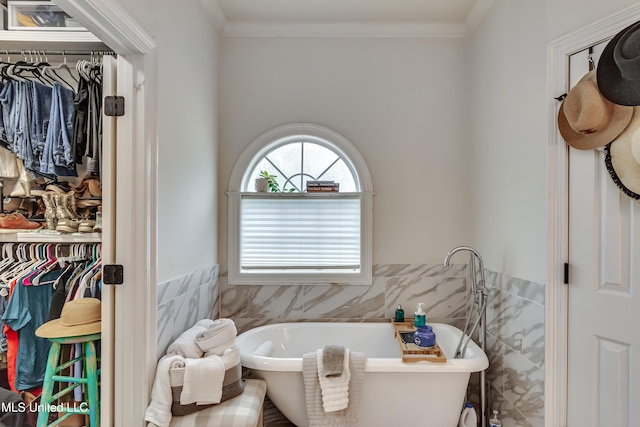 708 Oak Trl, Canton, MS 39046 - bathroom with tile walls, a spacious closet, a freestanding bath, a wainscoted wall, and crown molding