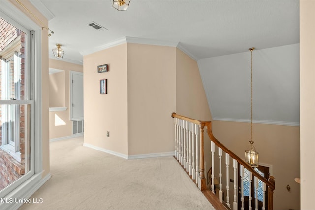 hallway featuring an upstairs landing, crown molding, visible vents, baseboards, and carpet floors