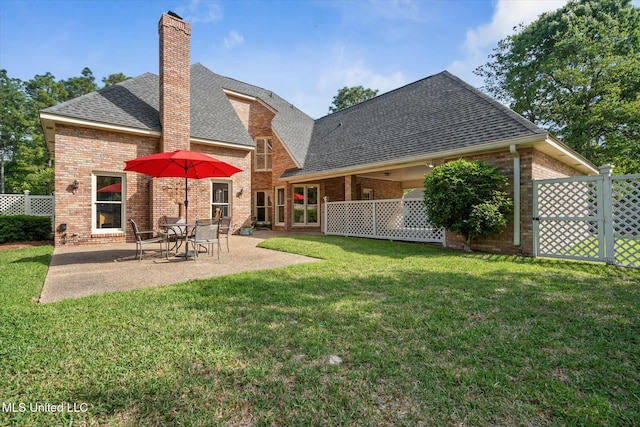 rear view of house featuring a chimney, a yard, brick siding, fence, and roof with shingles
