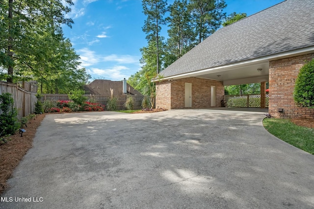 exterior space featuring concrete driveway, a shingled roof, and brick siding