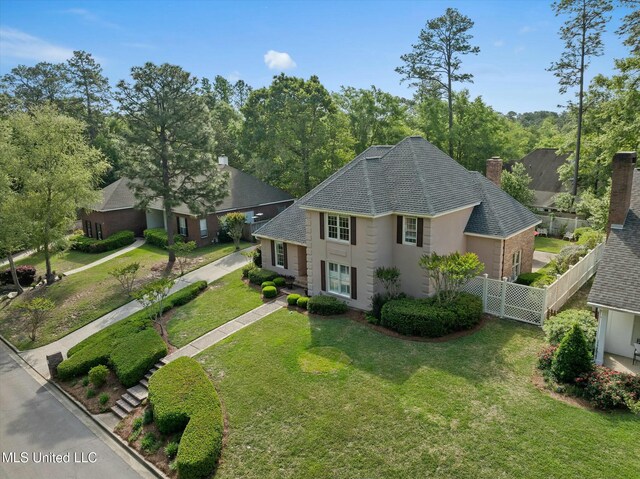 view of front of property featuring a front yard, a chimney, roof with shingles, stucco siding, and fence