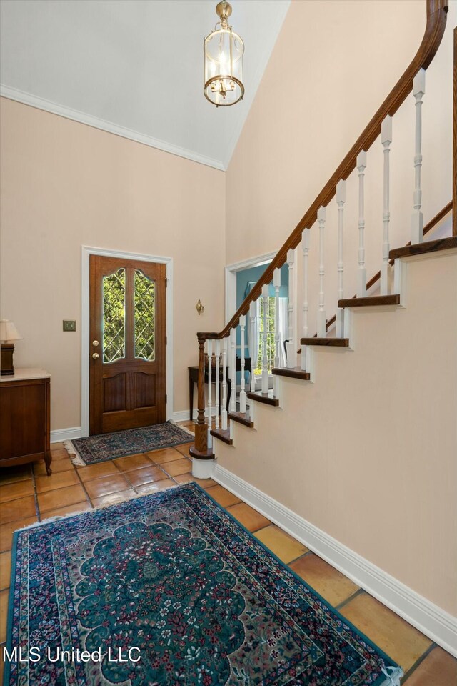 entrance foyer with a chandelier, stairway, tile patterned flooring, and high vaulted ceiling