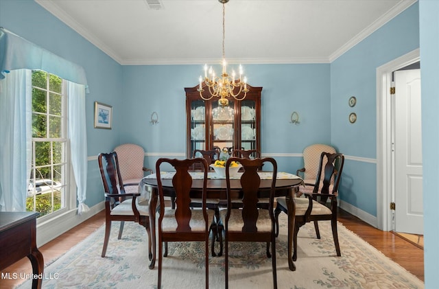 dining area featuring light wood-type flooring, a wealth of natural light, crown molding, and an inviting chandelier