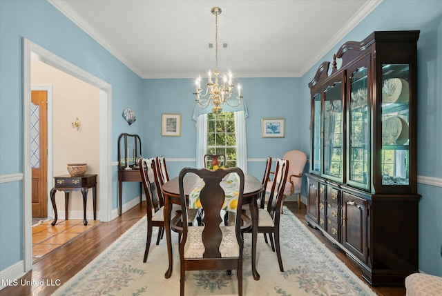 dining space with an inviting chandelier, crown molding, visible vents, baseboards, and wood finished floors