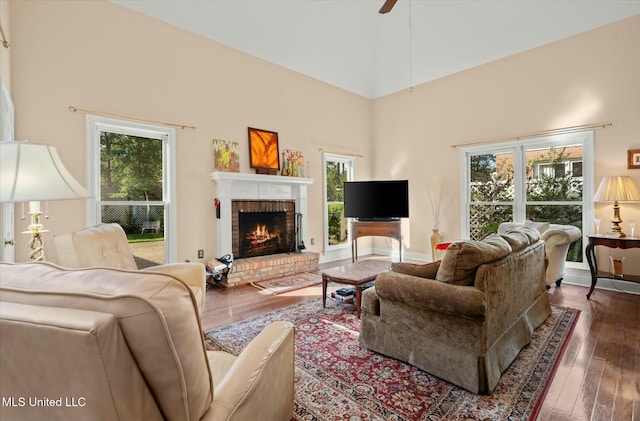 living area with hardwood / wood-style floors, a healthy amount of sunlight, and a brick fireplace