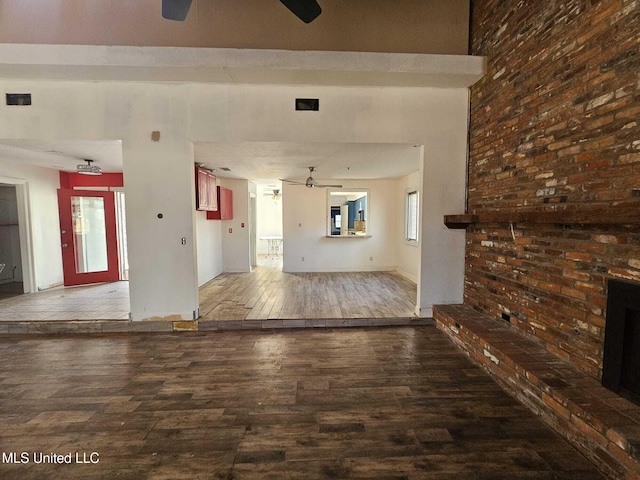 unfurnished living room with ceiling fan, wood-type flooring, and a fireplace