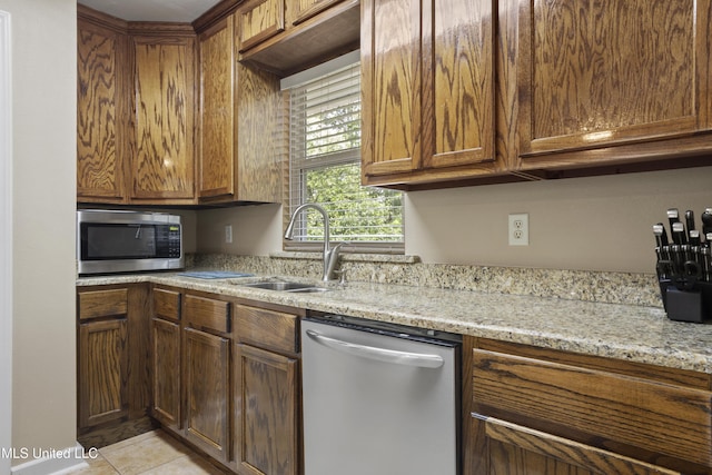 5297 Tuxachanie Dr, Biloxi, MS 39532 - kitchen featuring stainless steel appliances, a sink, light stone countertops, brown cabinets, and light tile patterned floors
