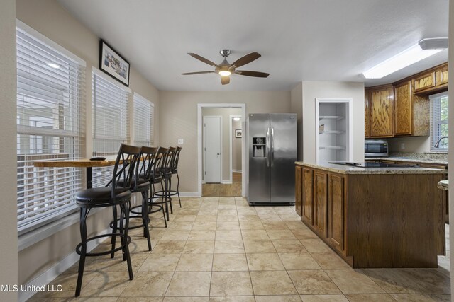 5297 Tuxachanie Dr, Biloxi, MS 39532 - kitchen featuring stainless steel fridge with ice dispenser, black electric cooktop, ceiling fan, baseboards, and a kitchen island