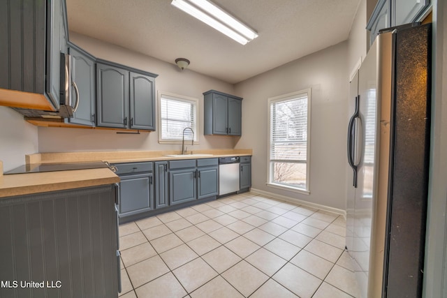 kitchen featuring light countertops, stainless steel appliances, a sink, and light tile patterned flooring