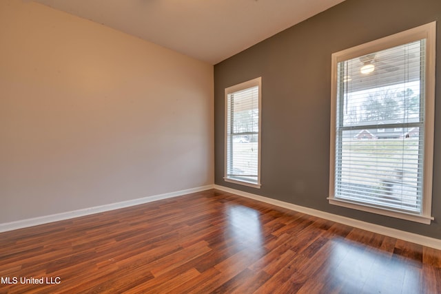 spare room with dark wood-type flooring, a healthy amount of sunlight, and baseboards