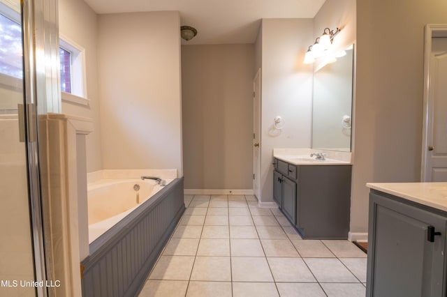 bathroom featuring a garden tub, baseboards, two vanities, and tile patterned floors