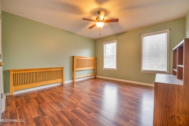 unfurnished room featuring ceiling fan, wood finished floors, and baseboards