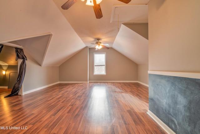 additional living space with attic access, vaulted ceiling, baseboards, and wood finished floors