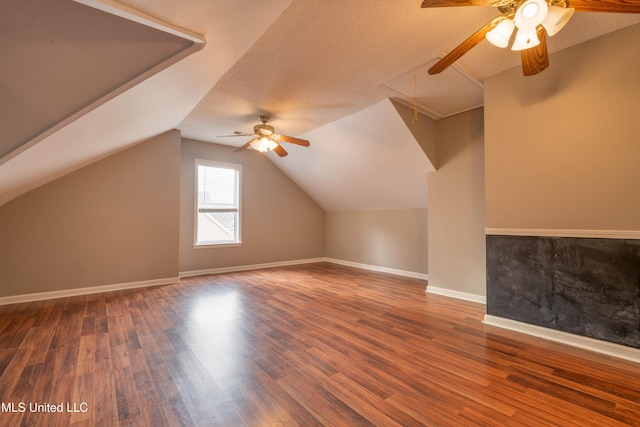 additional living space with attic access, a textured ceiling, baseboards, and wood finished floors