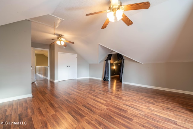 additional living space with vaulted ceiling, wood finished floors, attic access, and baseboards