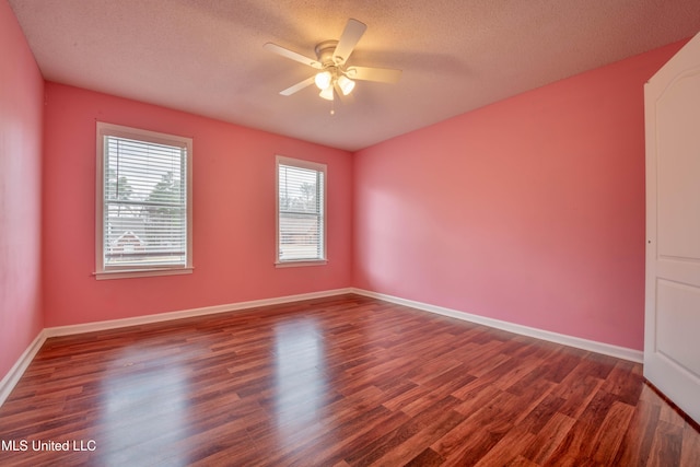 unfurnished room featuring dark wood-style floors, a ceiling fan, baseboards, and a textured ceiling