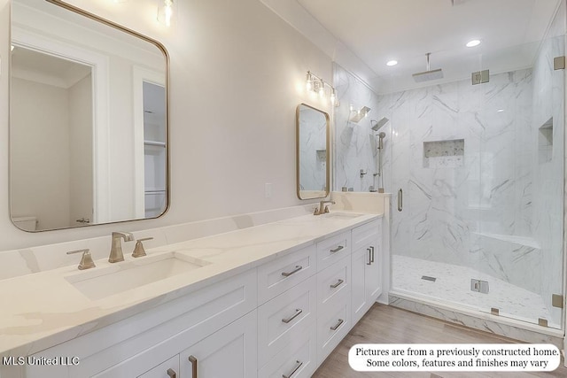 bathroom with a sink, a marble finish shower, recessed lighting, and double vanity