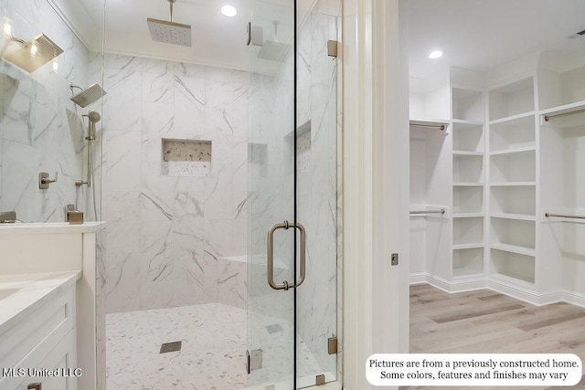 full bath featuring a marble finish shower, recessed lighting, wood finished floors, and a walk in closet
