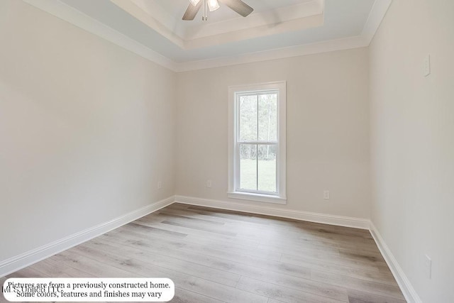 unfurnished room with ornamental molding, wood finished floors, baseboards, ceiling fan, and a raised ceiling