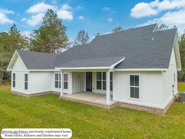 back of property featuring a shingled roof, board and batten siding, and a yard
