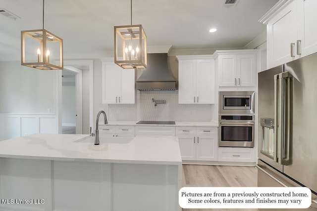 kitchen featuring visible vents, appliances with stainless steel finishes, a sink, premium range hood, and light countertops
