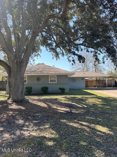 ranch-style house with concrete driveway, fence, and a front yard