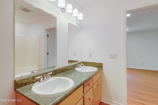 full bath featuring double vanity, wood finished floors, a sink, and visible vents