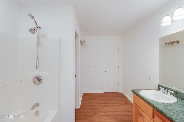 full bath featuring washtub / shower combination, wood finished floors, vanity, and baseboards