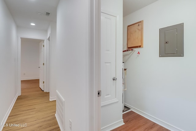 hallway with light wood-type flooring, electric panel, baseboards, and recessed lighting