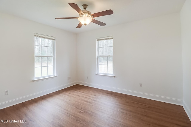 unfurnished room with dark wood-style floors, a wealth of natural light, and baseboards