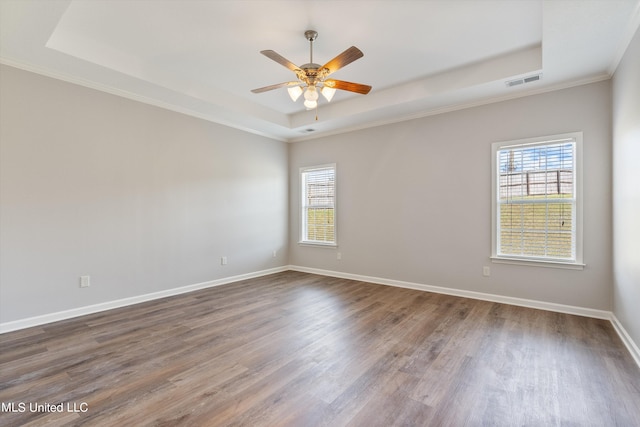 unfurnished room featuring crown molding, dark wood-type flooring, a tray ceiling, and ceiling fan