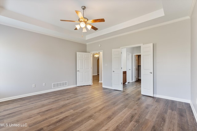 unfurnished bedroom featuring ceiling fan, crown molding, wood-type flooring, and a tray ceiling