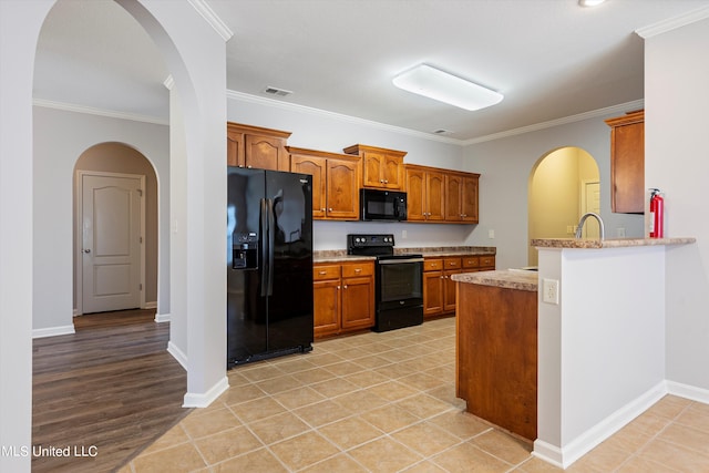 kitchen with black appliances, kitchen peninsula, crown molding, and light hardwood / wood-style floors