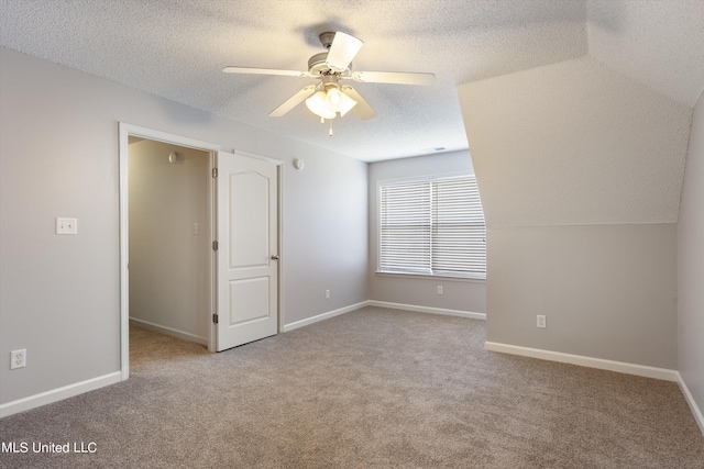 unfurnished bedroom featuring lofted ceiling, a textured ceiling, light colored carpet, and ceiling fan