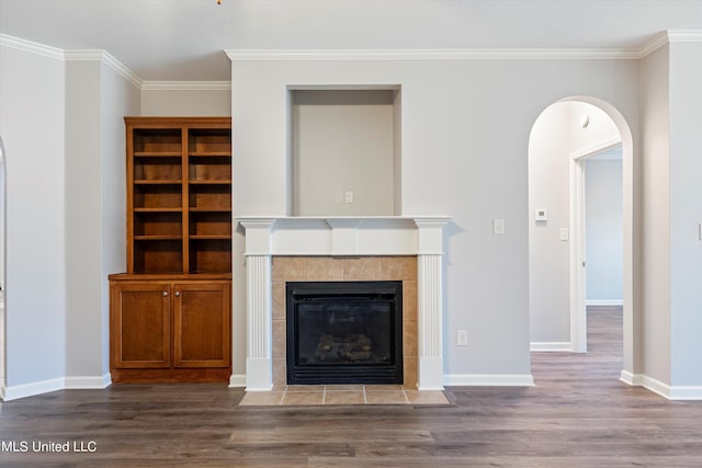 unfurnished living room with crown molding, a tiled fireplace, and dark hardwood / wood-style flooring