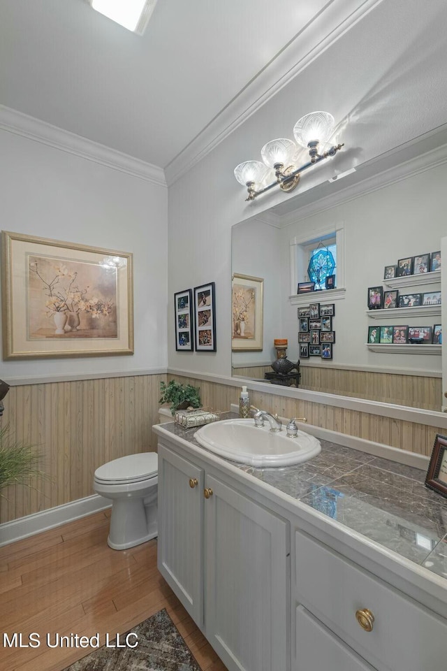 bathroom with toilet, vanity, ornamental molding, and hardwood / wood-style flooring