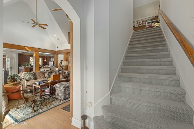 staircase featuring ceiling fan, wood-type flooring, and a towering ceiling