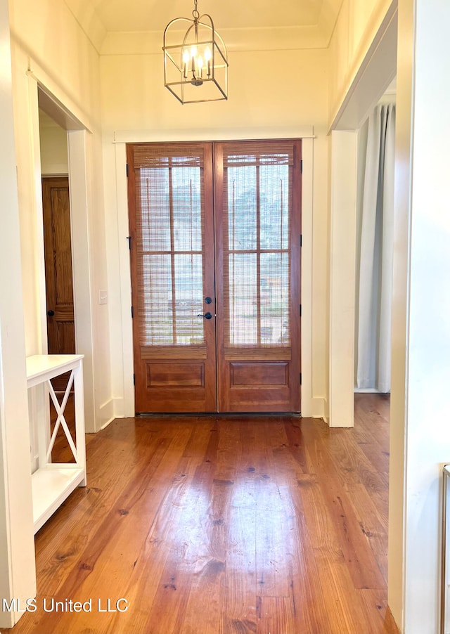 doorway featuring french doors, hardwood / wood-style floors, crown molding, and an inviting chandelier