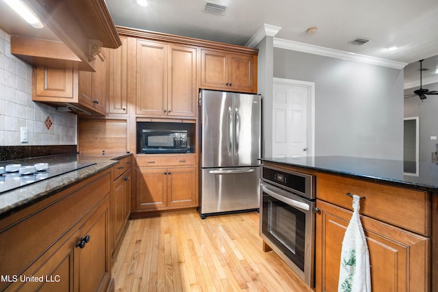 kitchen featuring dark stone countertops, crown molding, stainless steel appliances, and decorative backsplash