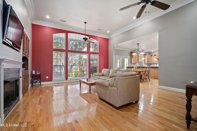 living room featuring ceiling fan, ornamental molding, and light hardwood / wood-style flooring