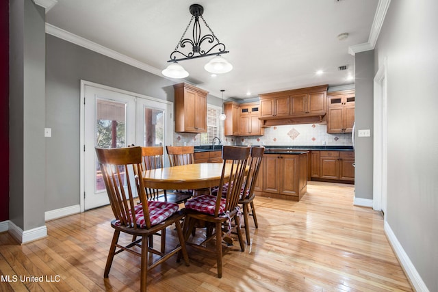 dining room with sink, light hardwood / wood-style flooring, and ornamental molding